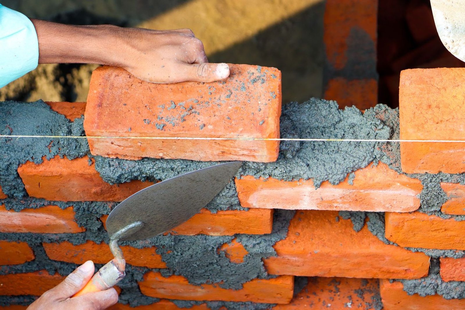 Mason laying brick with mortar